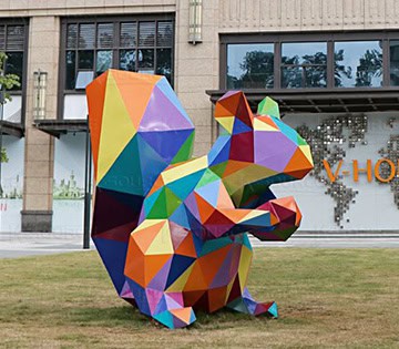 Large outdoor animal sculpture in the shape of a squirrel, with geometric sections and multi-color appearance