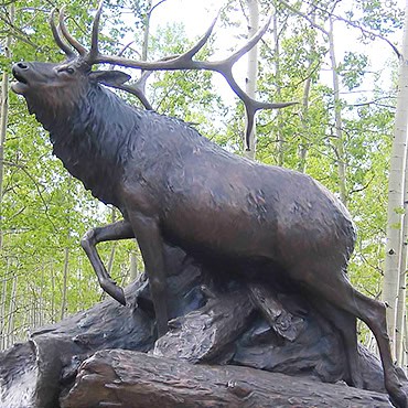 Life-sized elk standing on a tree stump base.